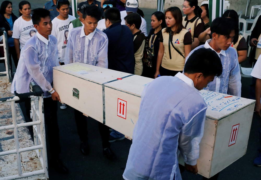 Funeral workers carry a crate containing the body of Joanna Demafelis, a Filipina domestic helper who was killed and found inside a freezer in Kuwait, in her hometown in Iloilo province in the Philippines February 17, 2018. Reuters/Erik De Castro