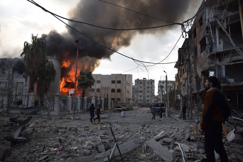 Citizens and fire fighters arrive to extinguish fire after Assad regime forces carried out an airstrike over the de-escalation zone in Douma town of Eastern Ghouta in Damascus, Syria on February 24, 2018. Mouneb Abu Taim / Anadolu Agency