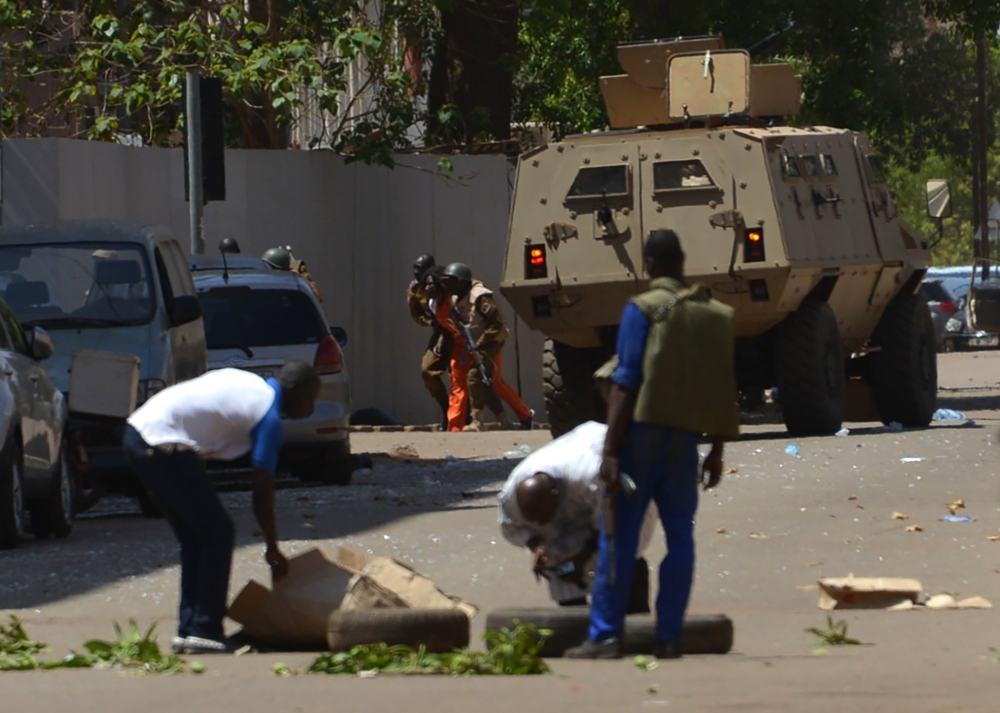 Bystanders look on as security personnel move beside an armoured personnel carrier in Ouagadougou on March 2, 2018, as the capital of Burkina Faso came under multiple attacks targeting the French embassy, the French cultural centre and the country's milit