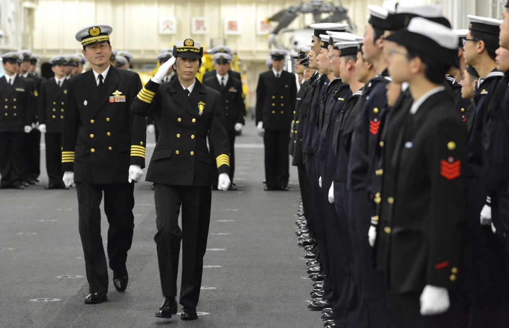 Newly-appointed Commander of First Escort Division of Japan Maritime Self-Defense Force (JMSDF) Ryoko Azuma (2nd L), who is the first female commander of a navy destroyer squadron in Japan, salutes to soldiers on JMSDF's helicopter carrier Izumo at a port
