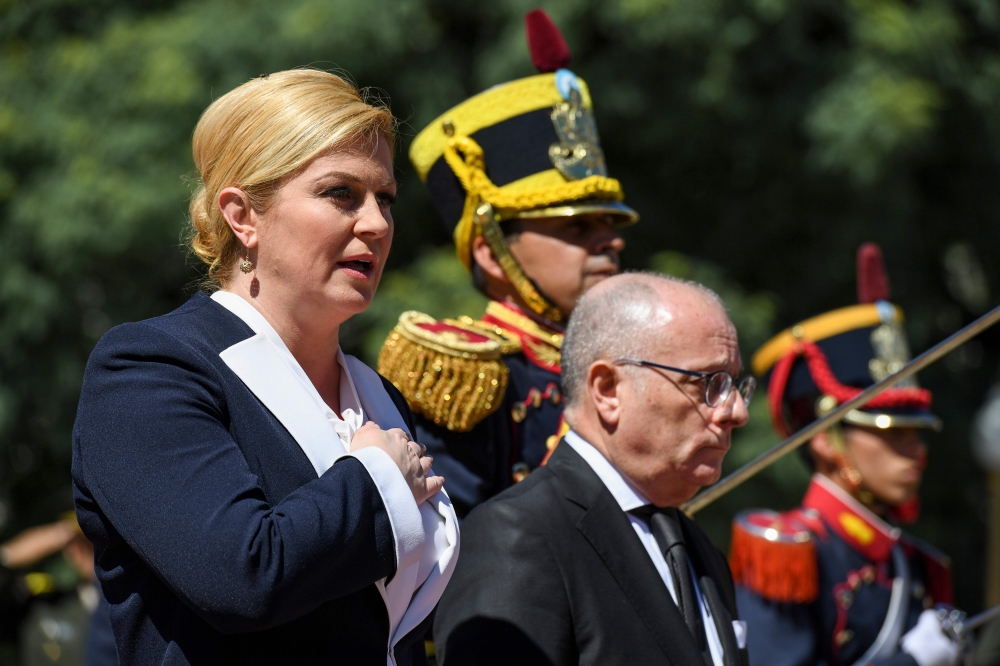 Croatian President Kolinda Grabar-Kitarovic (L) sings Croatia's national anthem next to Argentine Foreign Minister Jorge Faurie, during a wreath-laying ceremony to pay homage to Argentine national hero General Jose de San Martin, at San Martin square in B