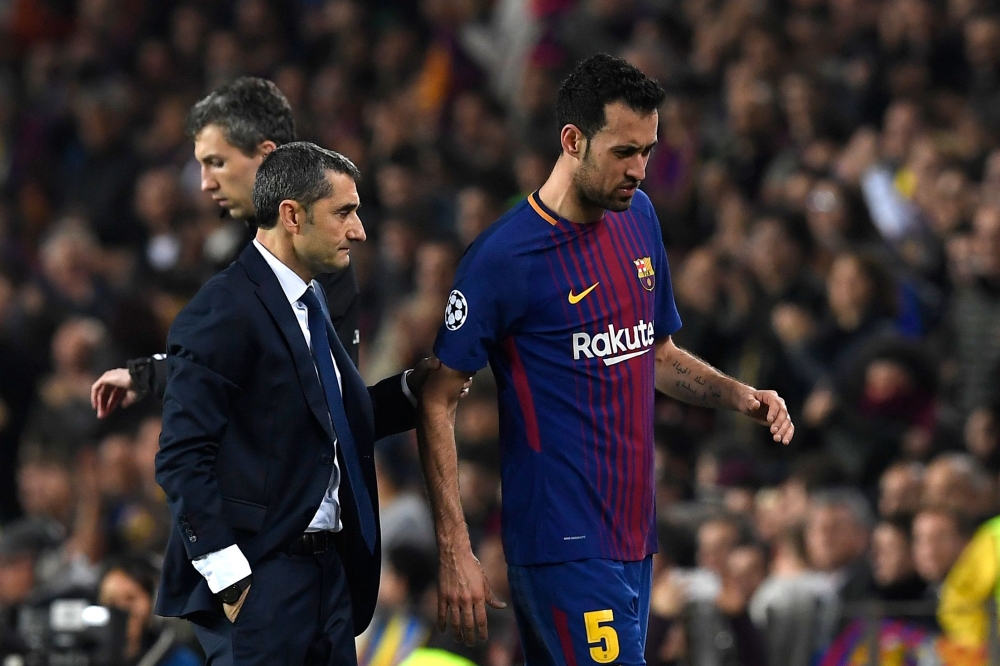 Barcelona's Spanish midfielder Sergio Busquets (R) walks with Barcelona's Spanish coach Ernesto Valverde as he is substituted during the UEFA Champions League round of sixteen second leg football match between FC Barcelona and Chelsea FC at the Camp Nou s