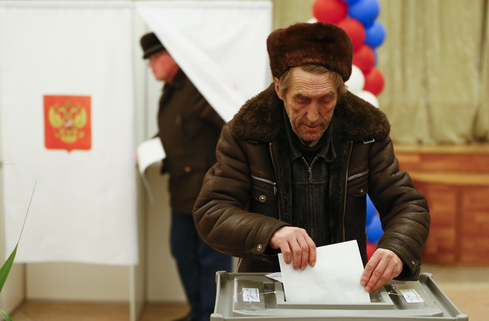 A Russian citizen casts a ballot at a polling station during the presidential election in Bakikonur, Kazakhstan March 18, 2018. REUTERS/Shamil Zhumatov