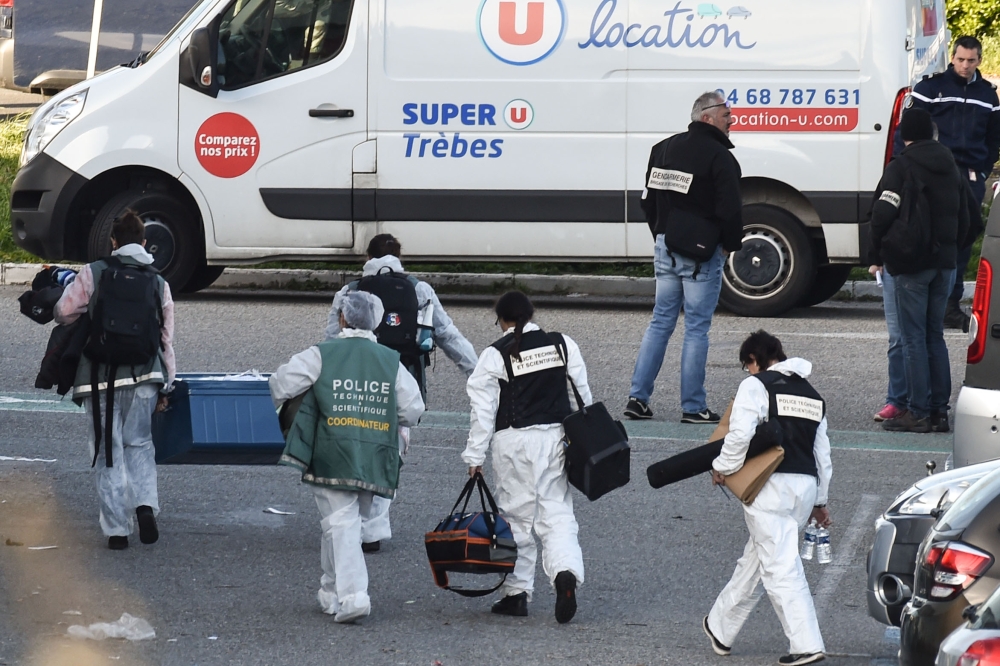 French forensic officers carry away material after a man took hostages at the Super U supermarket in the town of Trebes, southern France on March 23, 2018. AFP / Pascal Pavani