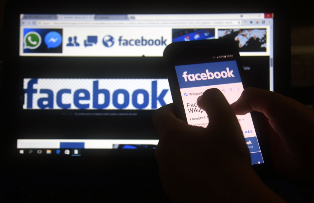 (FILES) In this file photo taken on March 22, 2018 a cellphone and a computer screen display the logo of the social networking site Facebook in Asuncion.   AFP / NORBERTO DUARTE

