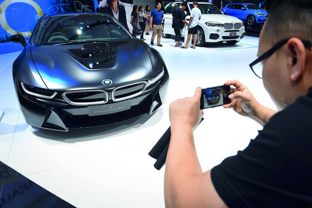 A man takes a photo of a BMW i8 hybrid sports car during the annual Bangkok International Motorshow in Bangkok on April 2, 2018. AFP / Lillian Suwanrumpha

