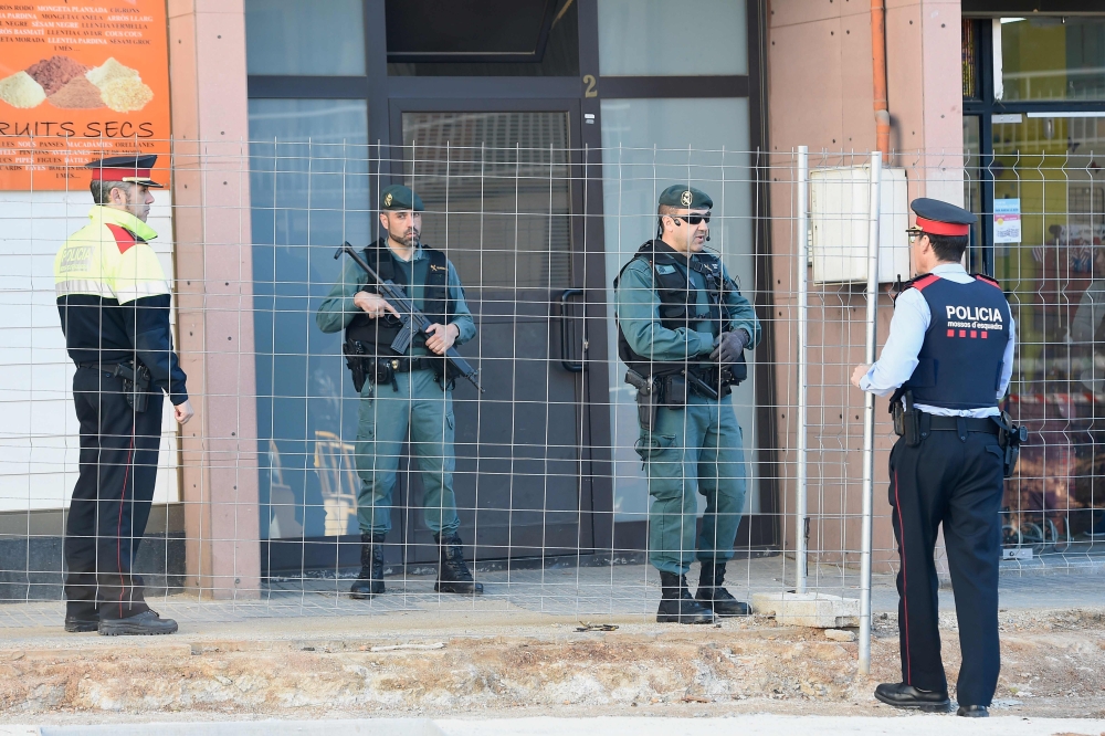 Spanish Guardia Civil guards and Catalan regional policemen Mossos d'Esquadra stand guard at the entrance of a building in Viladecans, near Barcelona, on April 10, 2018 where a member of the Republic Defence Committees (CDR), radical separatist groups, wa