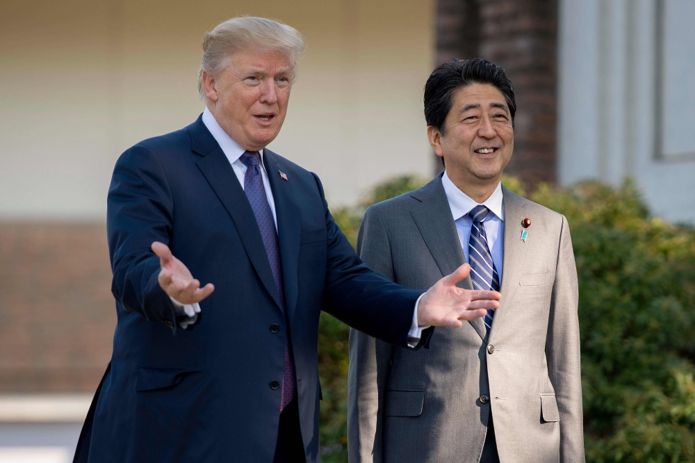 (FILES) In this file photo taken on November 5, 2017, US President Donald Trump (L) gestures as he speaks with Japan's Prime Minister Shinzo Abe upon his arrival for a luncheon at the Kasumigaseki Country Club Golf Course in Kawagoe, Saitama, outside Toky