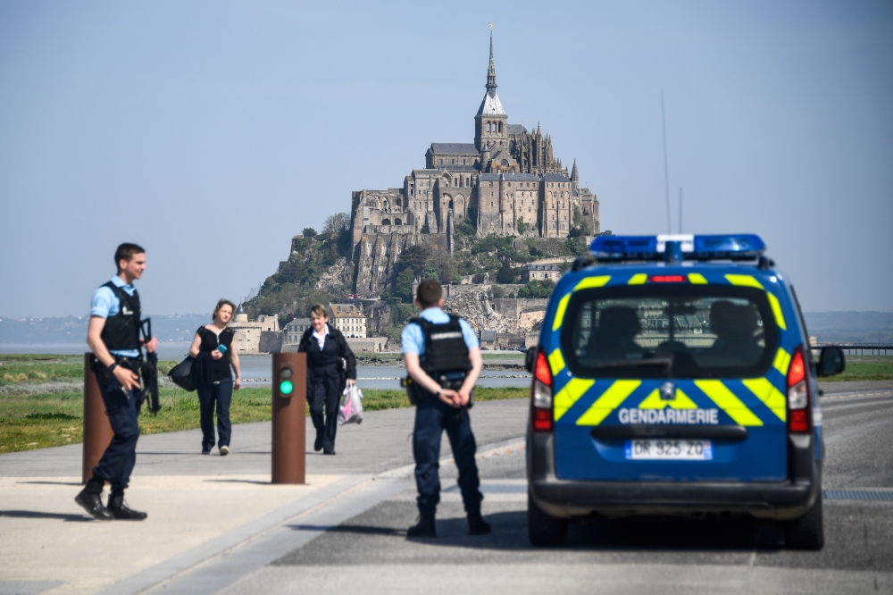 People stand on the road leading to the Mont-Saint-Michel as Gendarmes black the access after it was evacuated on April 22, 2018 of its tourists and residents 