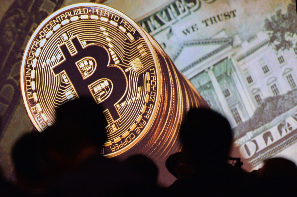 An image of Bitcoin and US currencies displayed on a screen as delegates listen to a panel of speakers during the Interpol World Congress in Singapore on July 04, 2017. (AFP / Roslan Rahma) 