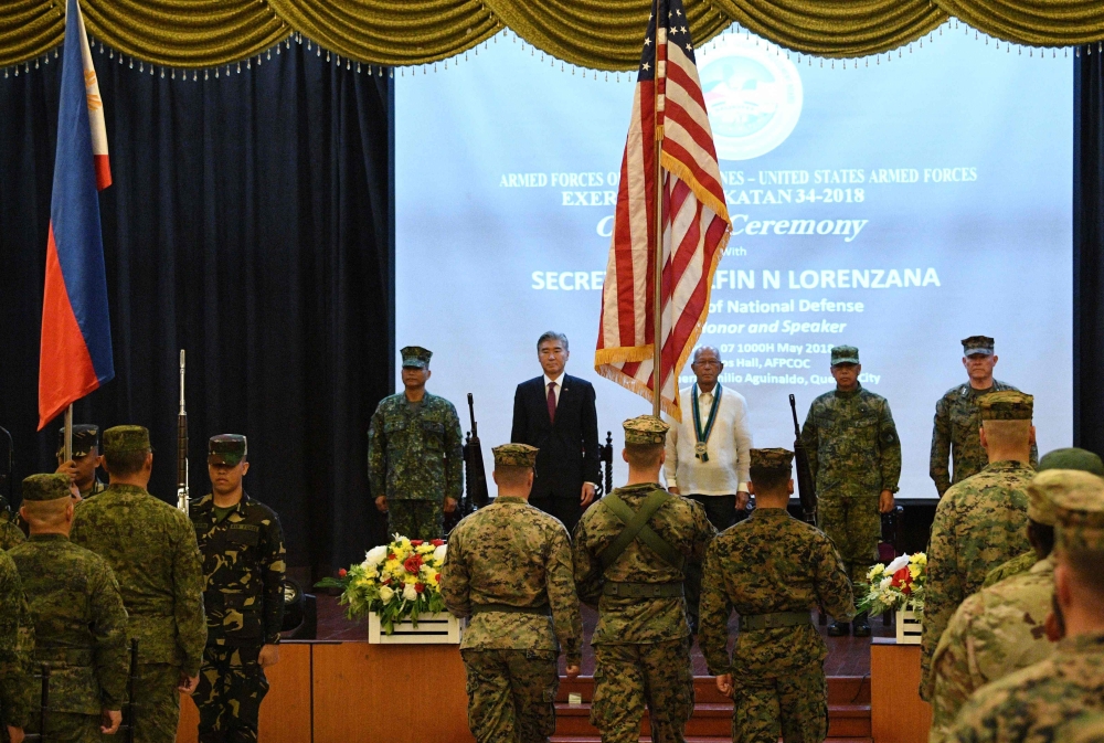 US military honour guards march with their national flag as US and Philippine officials stand at attention during the opening ceremony of the joint US and Philippines military exercise at the military headquarters in Manila on May 7, 2018.   AFP / TED ALJ
