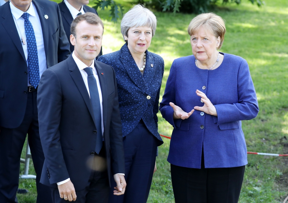 French President Emmanuel Macron (L) Britain's Prime Minister Theresa May( C) and German Chancellor Angela Merkel take a moment to pose for a photograph as they walk together during an EU-Western Balkans Summit in Sofia on May 17, 2018. AFP / LUDOVIC MARI