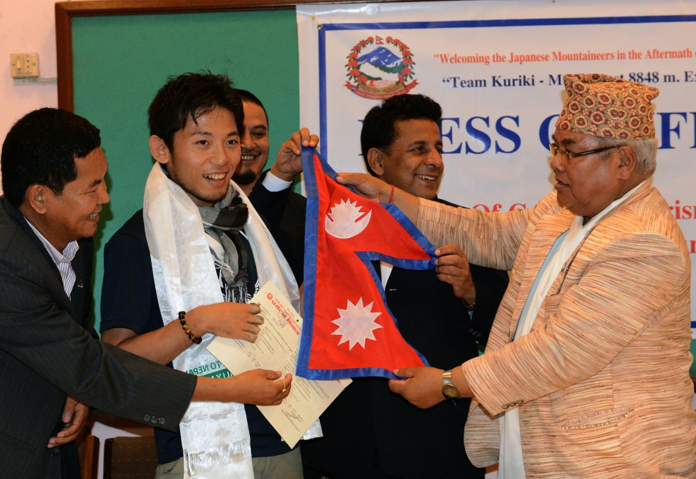In this file photo taken on August 23, 2015 Japanese climber Nobukazu Kuriki (2nd L) accepts a permit to climb Mount Everest and a Nepalese flag from Nepal's tourism minister Kripasur Sherpa (R) in Kathmandu.  / AFP / Prakash MATHEMA 