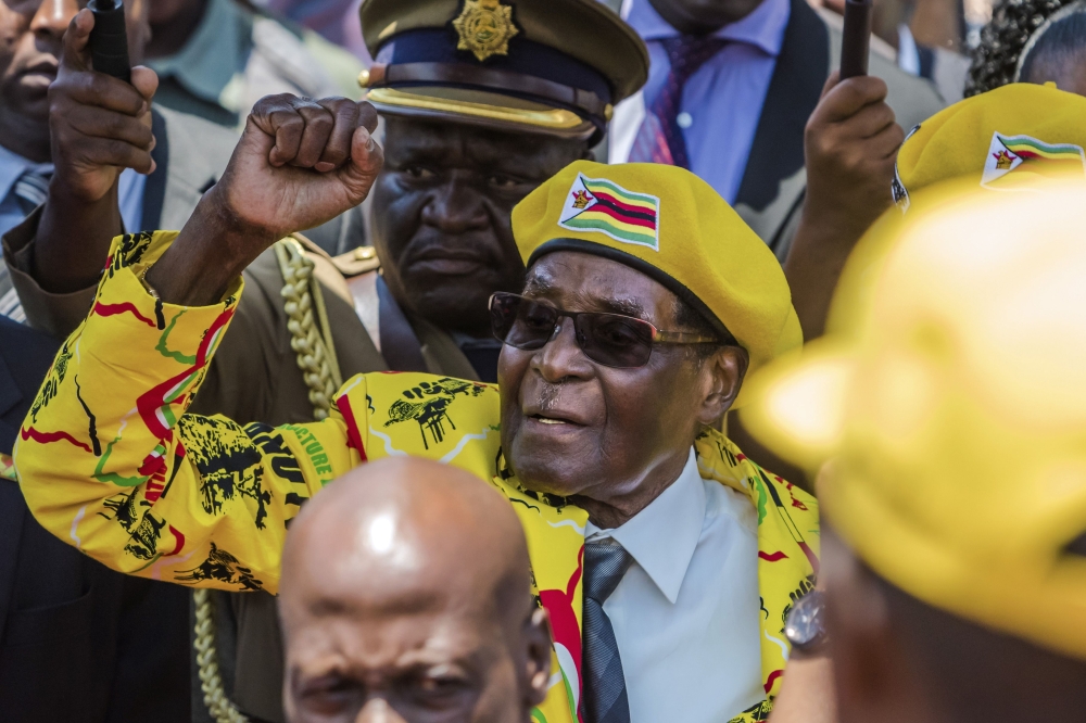 (FILES) In this file photo taken on November 8, 2017, shows Zimbabwe's President Robert Mugabe raising his fist as he greets party members and supporters gathered at his party headquarters to show support to Grace Mugabe becoming the party's next Vice Pre