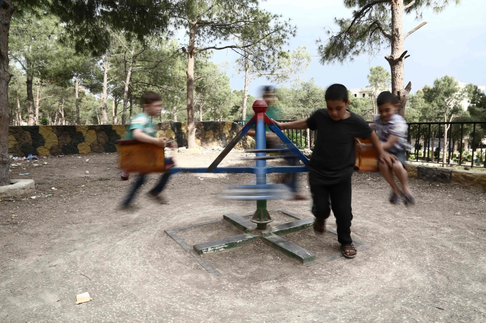 Syrian children displaced from Eastern Ghouta play in a park in Afrin on May 5, 2018.AFP / Nazeer AL-KHATIB
