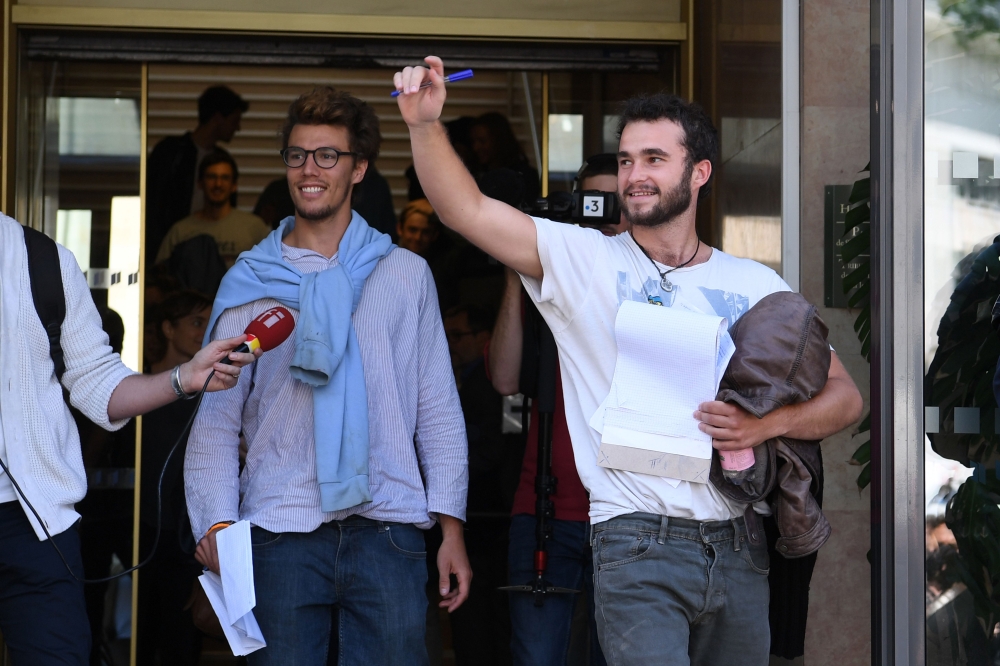 Swiss-Belgian Theo Buckmaster (R) and Swiss Bastien Stauffer (L) leave at a courthouse in Gap, in the French Alpes, after a hearing on May 31, 2018 on charges of helping migrants cross border into France.  AFP / Jean-Pierre Clatot