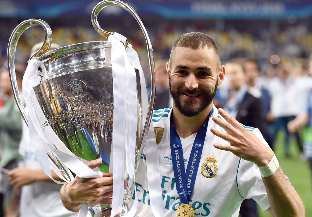 (FILES) In this file photo taken on May 26, 2018 Real Madrid's French forward Karim Benzema gestures the number four as he poses with the trophy after winning the UEFA Champions League final football match between Liverpool and Real Madrid at the Olympic 