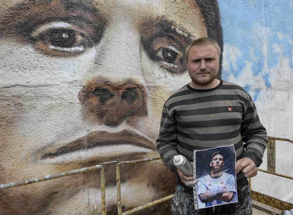 Russian street artist Sergey Erofeev poses next to his mural depicting Argentina's football star Lionel Messi in Bronnitsy near Moscow on June 9, 2018, ahead of the Russia 2018 World Cup.  AFP / Juan Mabromata