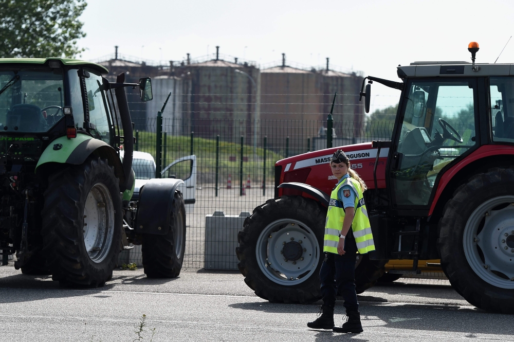 A French gendarme walks past tractors as French National federation of Agricultural Holders' Unions (FNSEA) and Young Farmers (Jeunes Agriculteurs, JA) union members block the access of a refinery in Reichstett, eastern France, on June 11, 2018 during a d