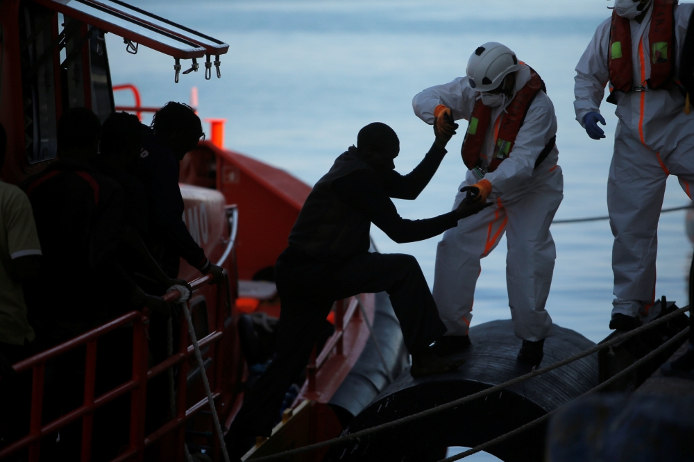 A migrant, part of a group intercepted aboard a dinghy off the coast in the Mediterranean Sea, is helped by a rescuer after arriving on a rescue boat at the port of Malaga, Spain June 22, 2018. REUTERS/Jon Nazca
