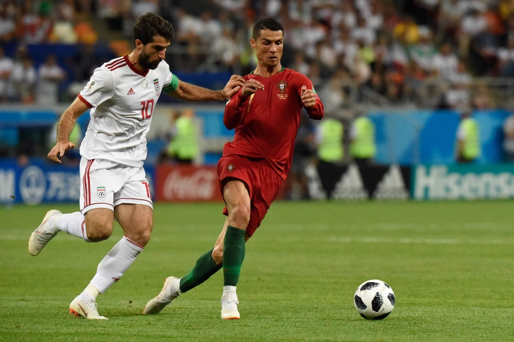 Portugal's forward Cristiano Ronaldo (R) is marked by Iran's forward Karim Ansari Fard during the Russia 2018 World Cup Group B football match between Iran and Portugal at the Mordovia Arena in Saransk on June 25, 2018.  AFP / JUAN BARRETO 
