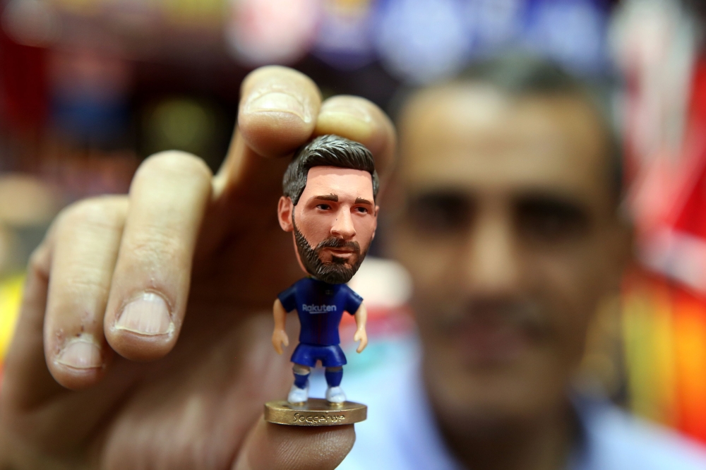 A sports shop keeper holds a figurine of Argentine football player Lionel Messi at a shop in Kuwait City on April 11, 2018. (AFP / Yasser Al-Zayyat) 