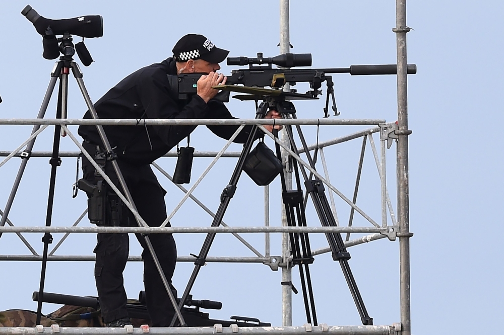 A police marksman awaits the arrival of US President Donald Trump on Air Force One at Prestwick Airport, south of Glasgow on July 13, 2018, on the second day of Trump's UK visit.  AFP / Andy Buchanan