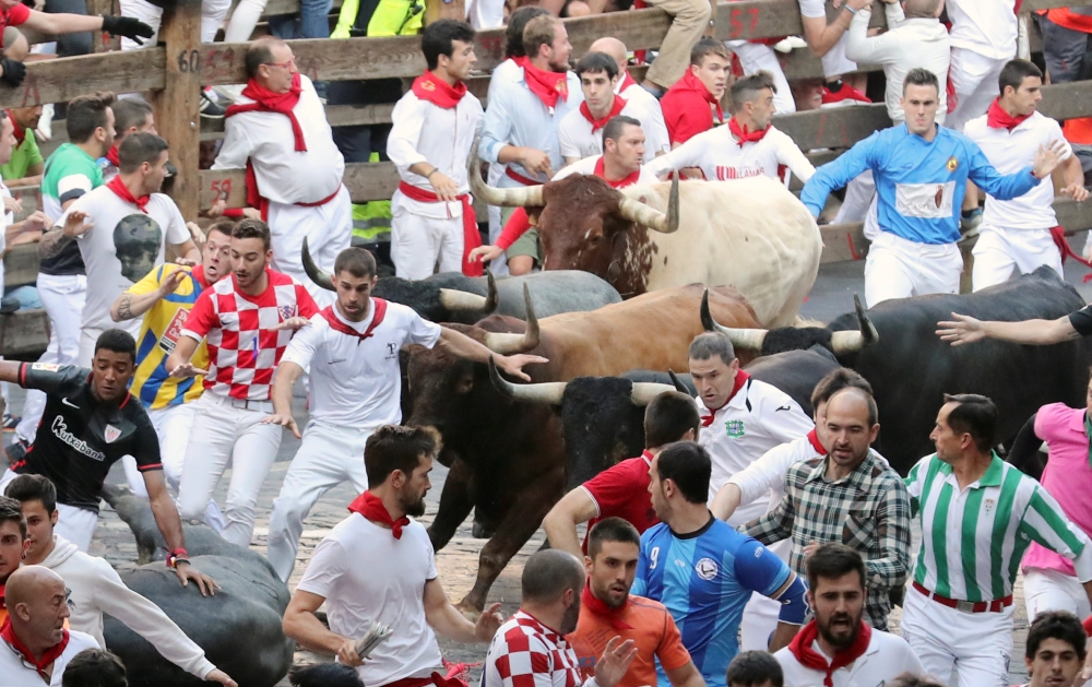 Runners sprint in front of the bulls during the last running of the bulls at the San Fermin festival in Pamplona, Spain, July 14, 2018. REUTERS/Susana Vera