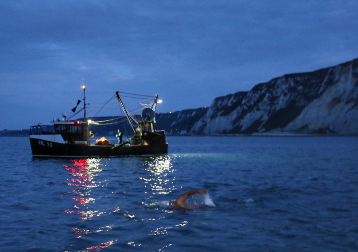 One of team members starts off his swim in the dark with white cliffs of Dover in background.