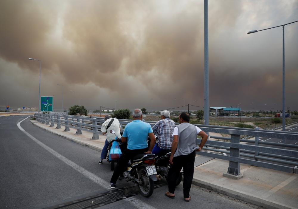 People look at smoke as a wildfire burns in Kineta, near Athens, Greece, July 23, 2018. Reuters/Alkis Konstantinidis