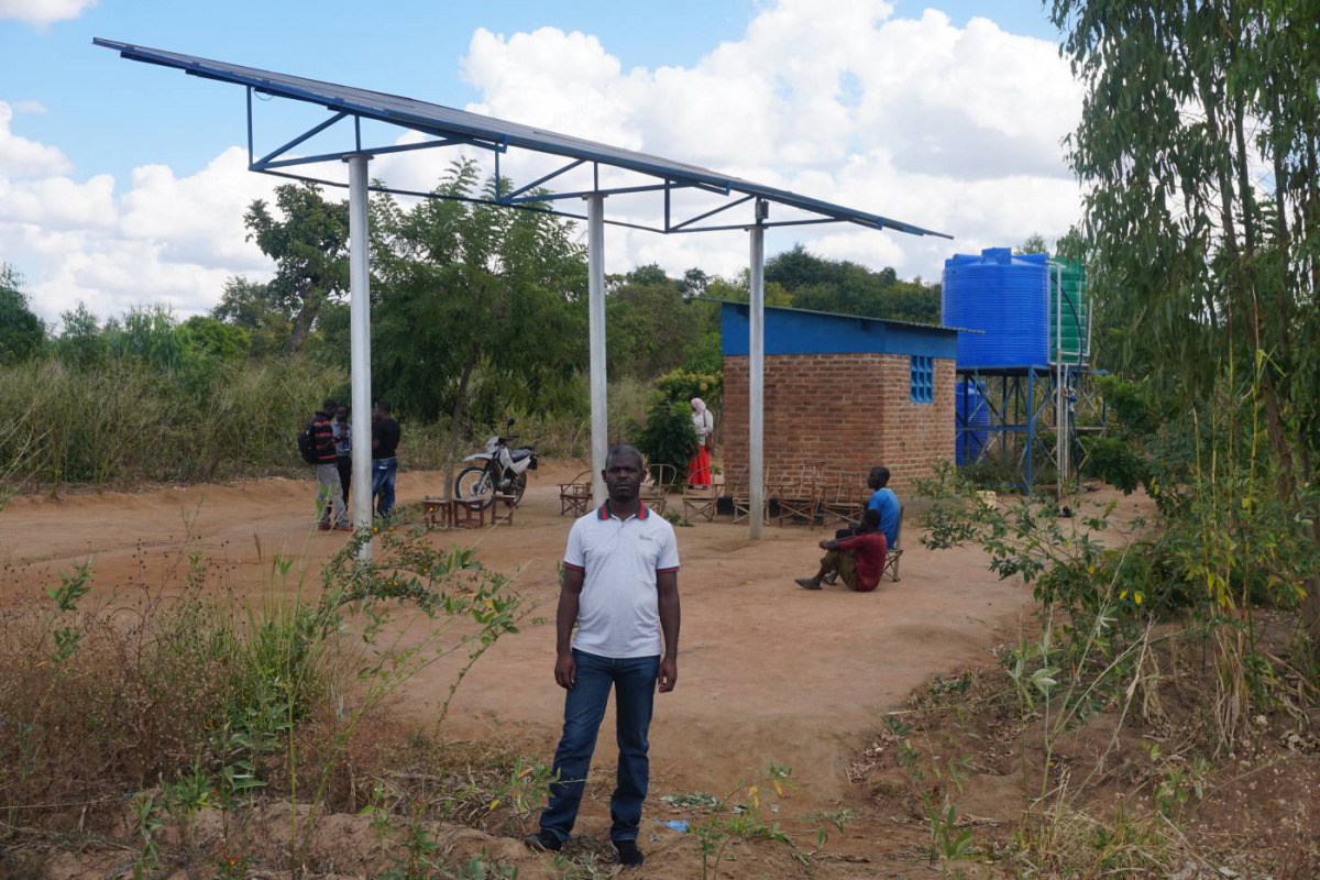 A man stands near a raised solar panel raised and reservoir tanks used for irrigation at Chiswamafupa irrigation scheme, in the traditional authority of Mambo in Zomba district, eastern Malawi, July 11, 2018. Thomson Reuters Foundation/Charles Mkoka