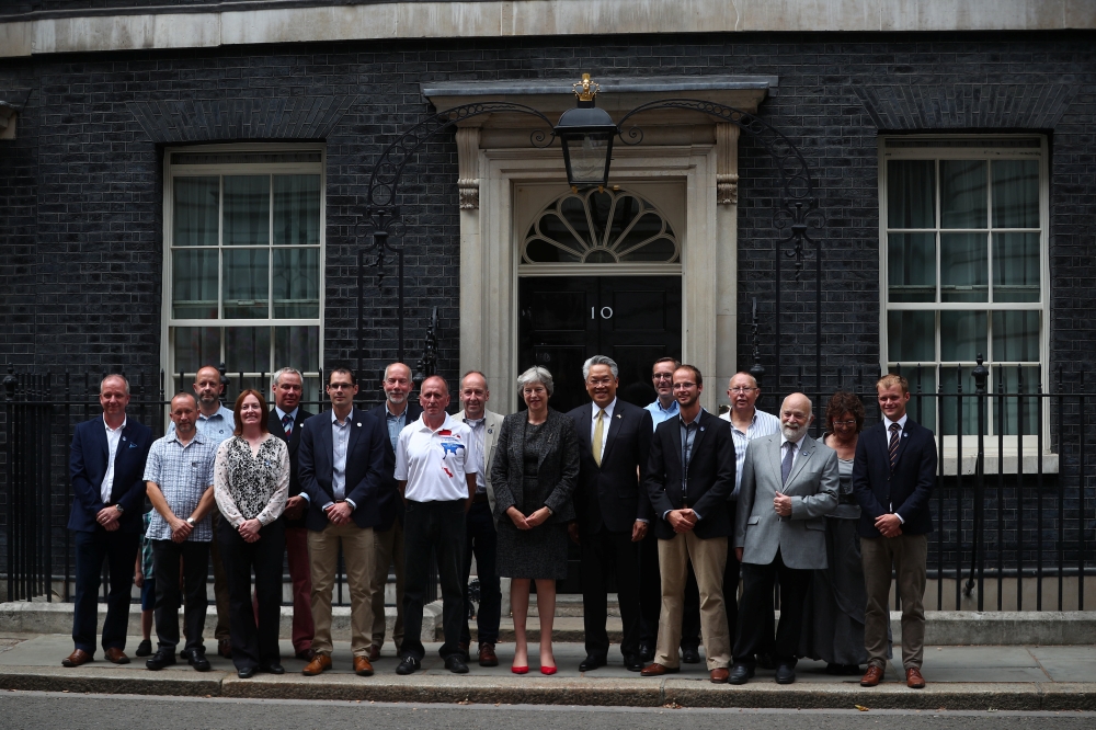 Britain's Prime Minister, Theresa May poses for a photograph with Thailand's Ambassador to the United Kingom, Pisanu Suvanajata, and the British cave divers and their suport team who helped rescue boys from a flooded cave in Thailand, in front of 10 Downi