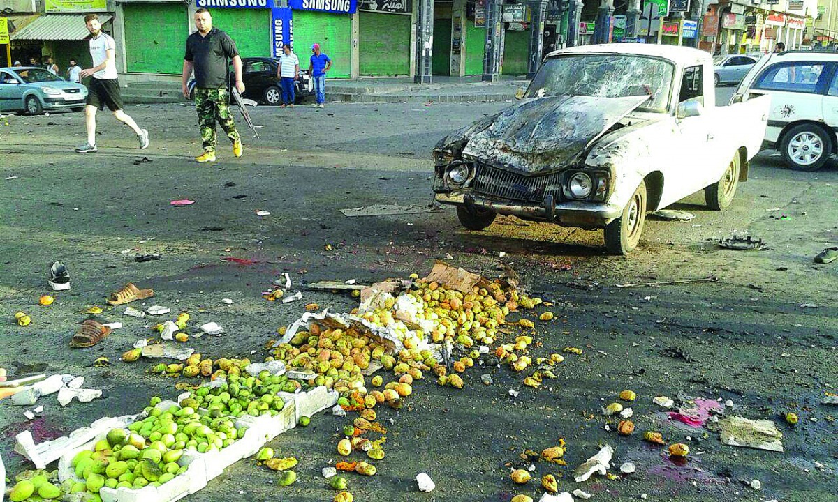 A handout picture released by the official Syrian Arab News Agency (SANA) on July 25, 2018 shows a member of the Syrian security forces walking past a truck damaged in a suicide attack in the southern city of Sweida. A string of suicide attacks in Syria b