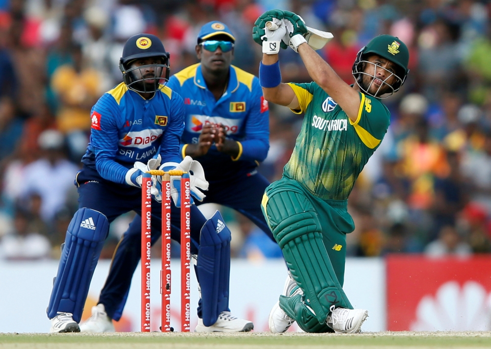 South Africa's Jean-Paul Duminy (R) hits a boundary next to Sri Lanka's wicketkeeper Niroshan Dickwella (L) and captain Angelo Mathews (C). REUTERS/Dinuka Liyanawatte
