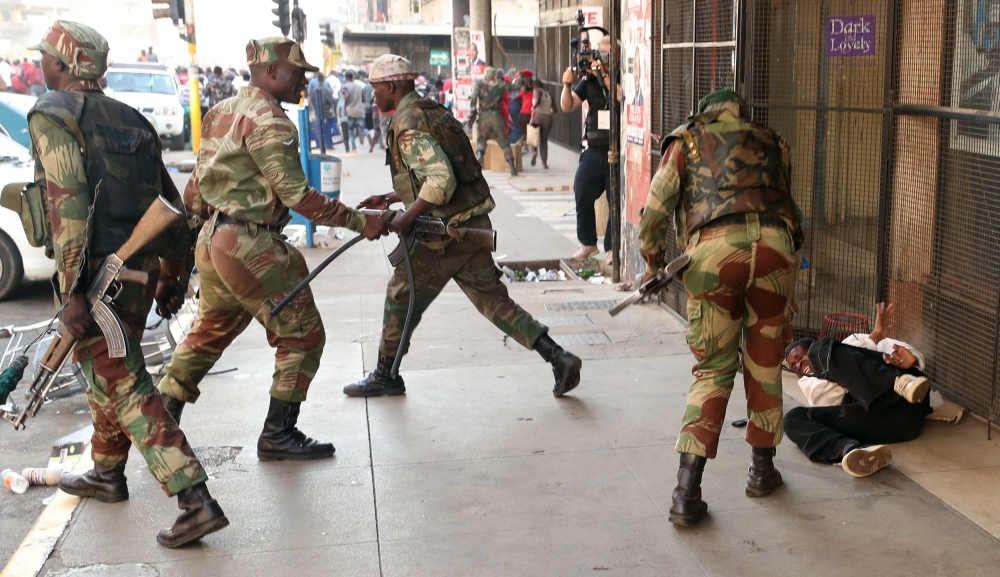 Soldiers beat a supporter of the opposition Movement for Democratic Change (MDC) outside the party's headquarters as they await election results in Harare, Zimbabwe, August 1, 2018. Reuters/Mike Hutchings
 