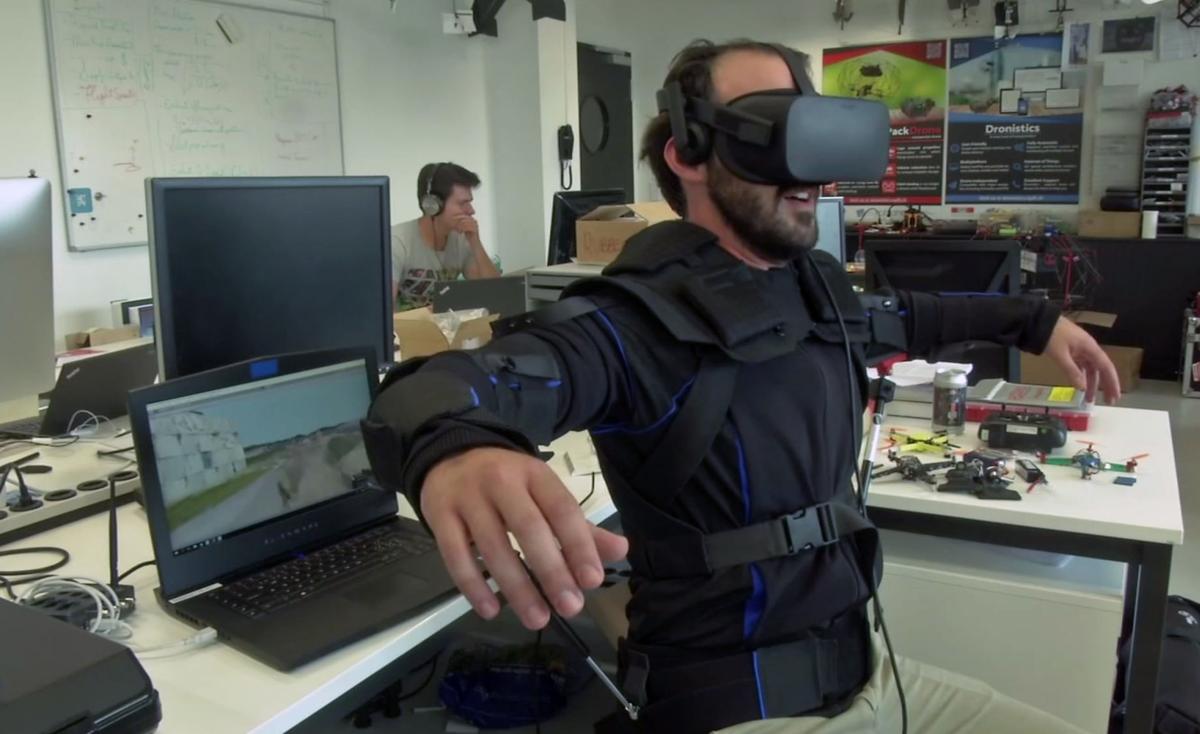 Robotics expert on the Ecole Polytechnique Federal de Lausanne, EPFL team, Matteo Macchini, right, displays the fly controls in a virtual reality scenario as he controls the flight of a drone in foreground, while observed by a fellow member of the team, J