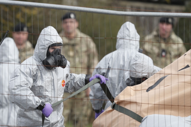 British military personnel wearing protective coveralls work to remove a vehicle connected to the March 4 nerve agent attack in Salisbury from a residential street in Gillingham on March 14, 2018. (AFP / Adrian Dennis) 