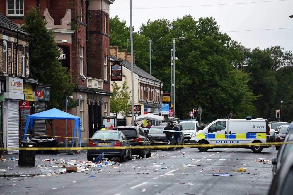 Police officers stand guard at the scene of a shooting at Claremont Road in the Moss Side neighbourhood of Manchester, on August 12, 2018. (AFP / Oli SCARFF)