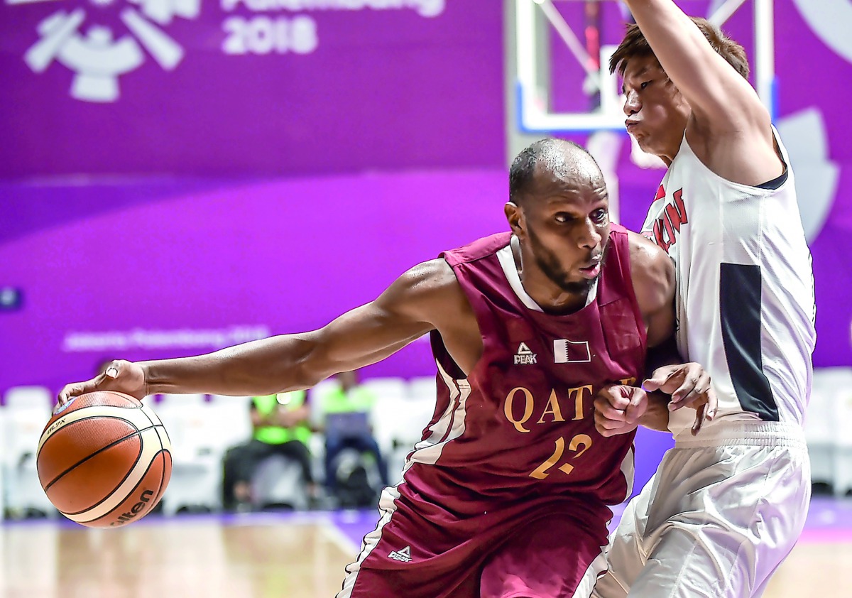 Qatar’s Khalid Abdi (left) dribbles past Hong Kong’s Cheng Kam Hing during their Group C basketball match in  the 2018 Asian Games in Jakarta yesterday.