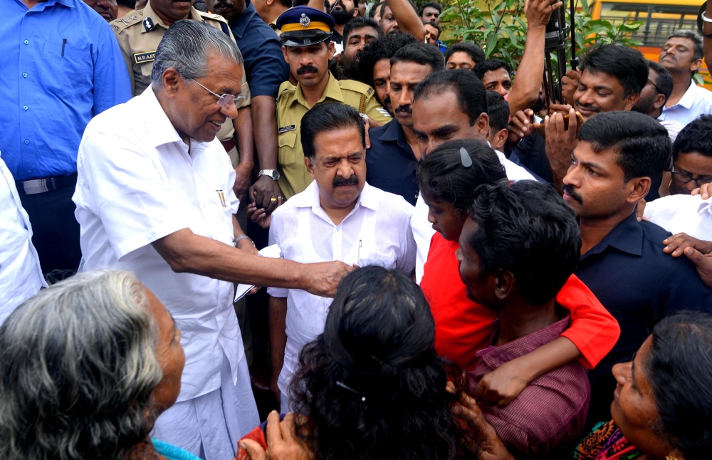 Kerala Chief Minister Pinarayi Vijayan (L) along with opposition leader Ramesh Chennithala (2L) visit a relief camp in Chengamanadu Government Higher Secondary School (HSS) in Ernakulam district of Kochi, in the Indian state of Kerala on August 11, 2018. 