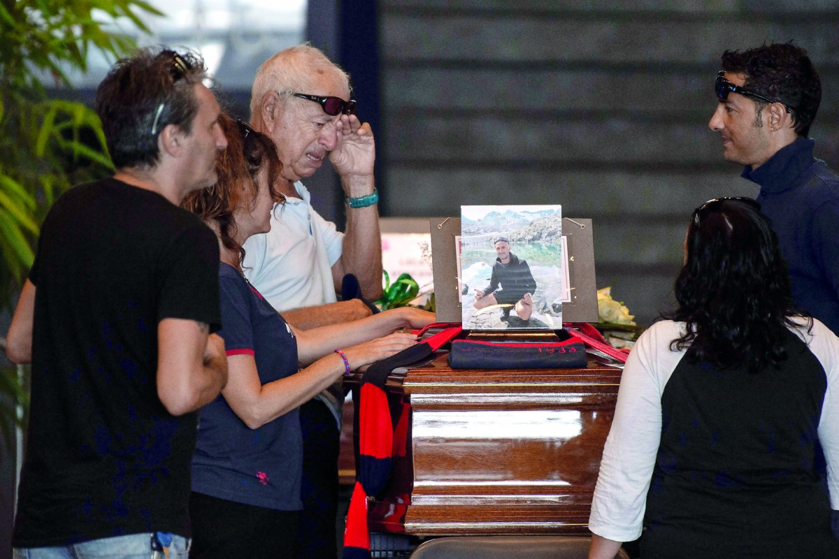 Relatives pray and pay their respects near the coffin of a victim of the Morandi bridge's collapse, in Genoa, on August 17, 2018. AFP / Marco Bertorello
 