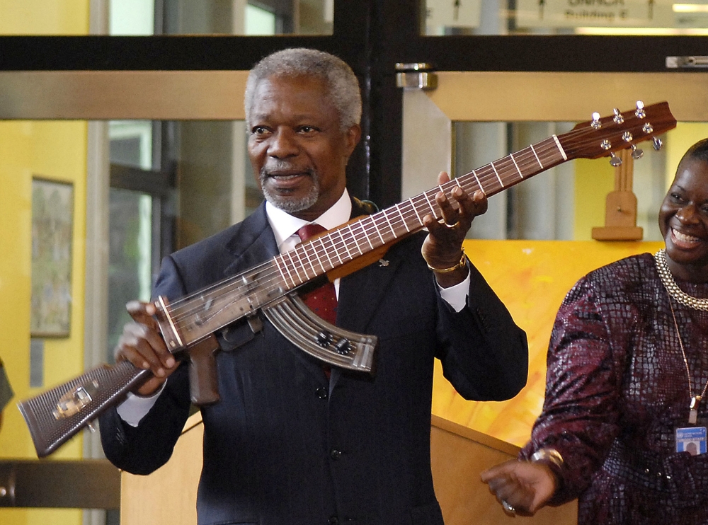 In this file photo Former UN Secretary-General Kofi Annan shows an AK-47 assault rifle that has been transformed into a guitar in front of workers at Vienna's United Nations headquarters. (AFP / SAMUEL KUBANI)