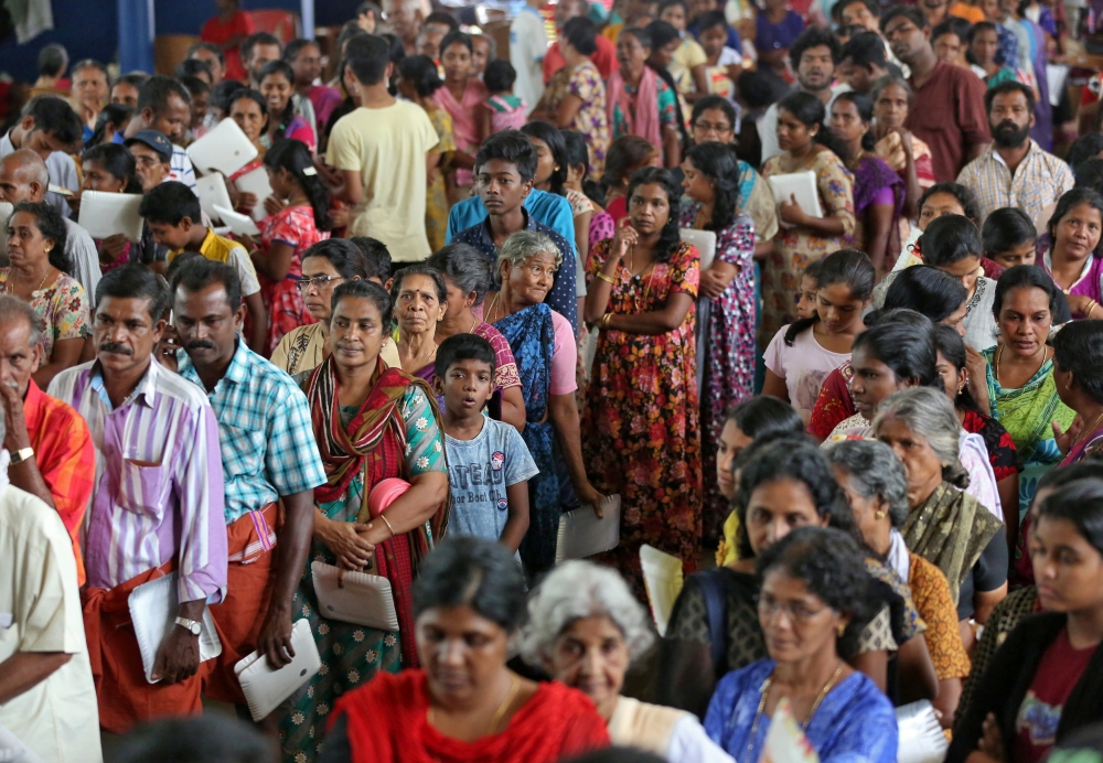 Flood-affected people wait to receive food inside a college auditorium, which has been converted into a temporary relief camp, in Kochi in the southern state of Kerala, India, August 20, 2018. (REUTERS/Sivaram V)