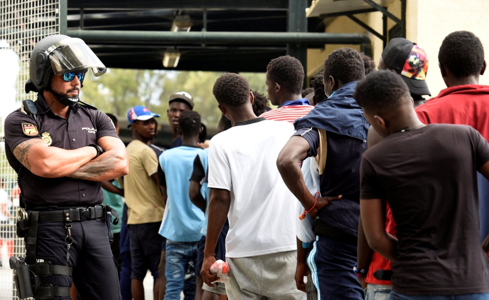 African immigrants wait in a row as they enter the immigrant center CETI in the Spanish enclave Ceuta, after some 200 refugees crossed the border fence between Morocco and Ceuta August 22, 2018. REUTERS/Fabian Bimmer
