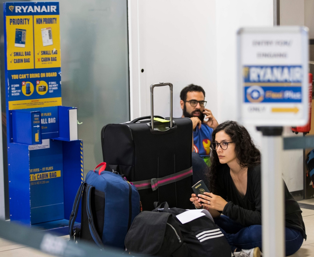 (FILES) In this file photo taken on August 10, 2018, Ryanair passengers sit on the terminal floor at Schoenefeld Airport in Berlin, after their Ryanair flight was cancelled because of a pilots strike. AFP / Odd ANDERSEN