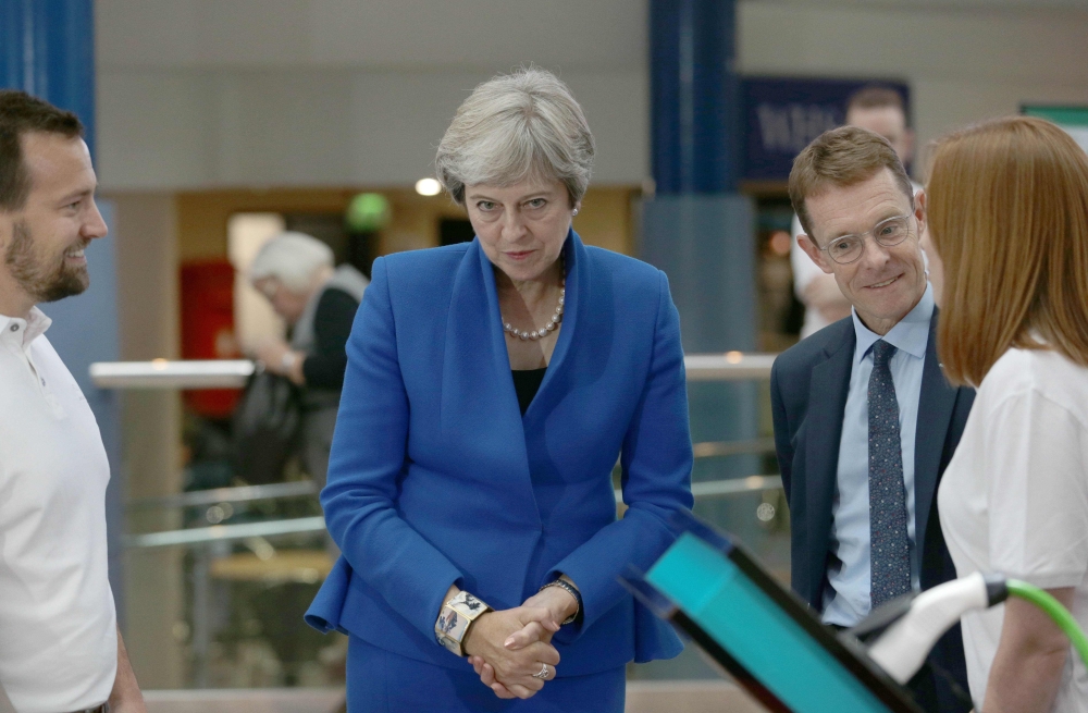 Britain's Prime Minister Theresa May (C) greets participants at the Zero Emission Vehicle Summit in Birmingham, central England on September 11, 2018. / AFP / POOL / Aaron Chown