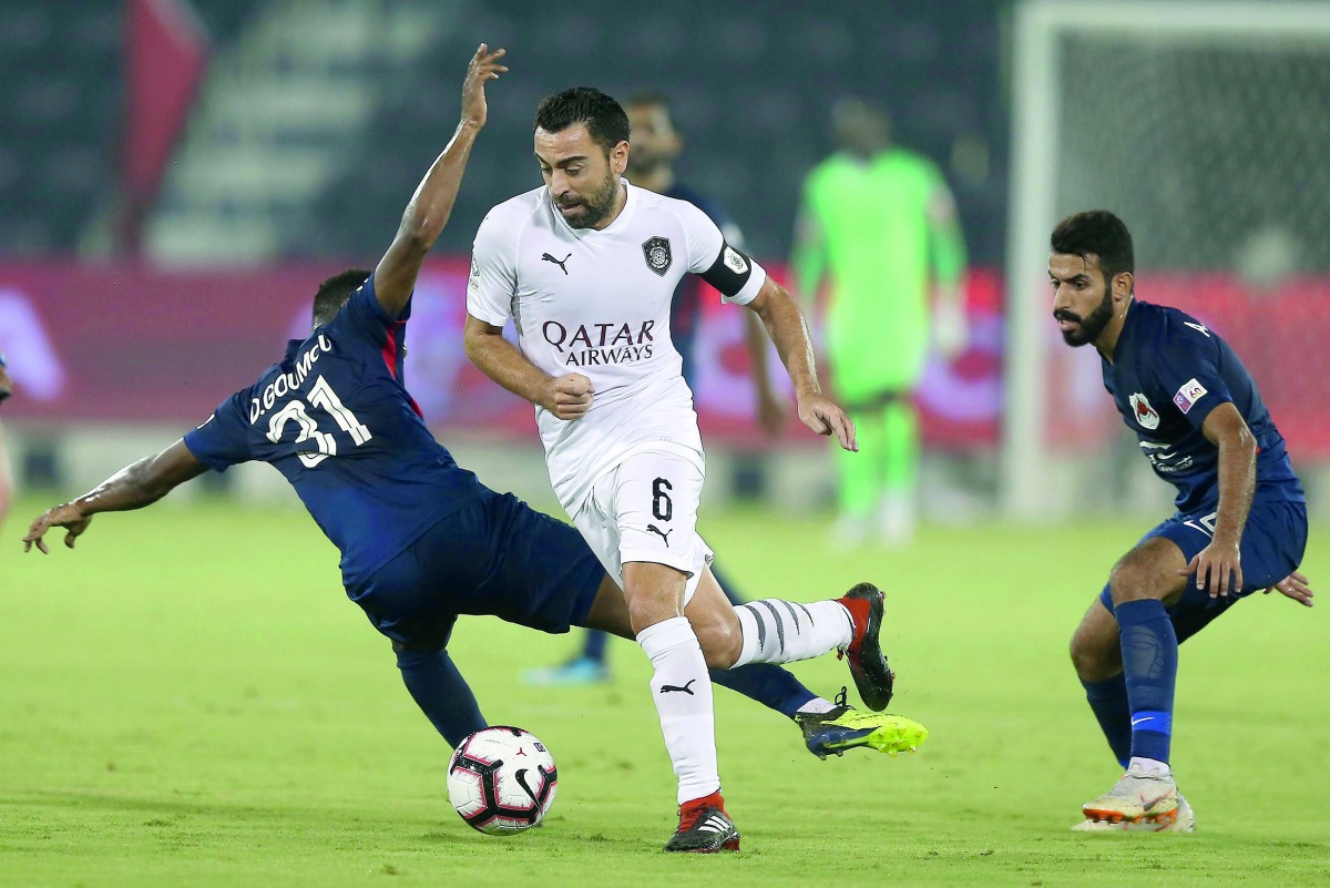 Al Sadd’s Xavi Hernandez (centre) weaves his way past a couple of Al Rayyan players during the QNB Stars League match in Doha yesterday.
