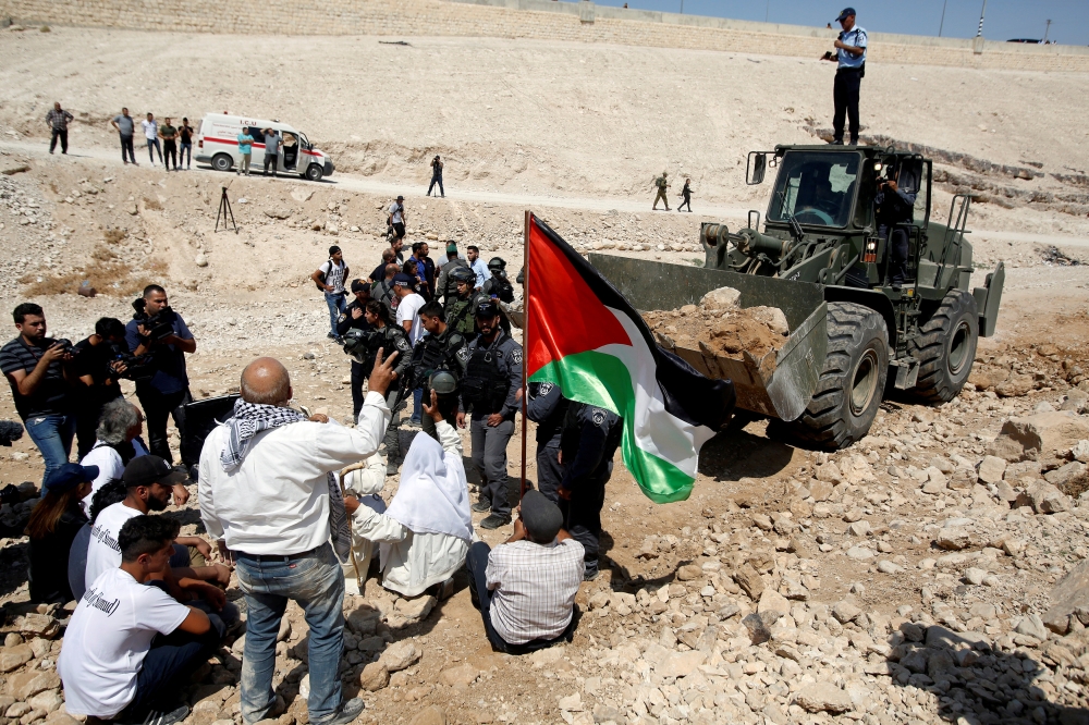 Palestinians gather in front of an Israeli bulldozer as they protest against Israel's plan to demolish the Palestinian Bedouin village of Khan al-Ahmar, in the occupied West Bank September 14, 2018. Reuters/Mussa Qawasma