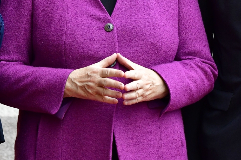 German Chancellor Angela Merkel holds her hands in her typical 