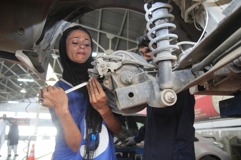 In this picture taken on September 1, 2018, Pakistani motor mechanic Uzma Nawaz, 24, fixes a car at an auto workshop in Multan.  / AFP / S.S. Mirza 
